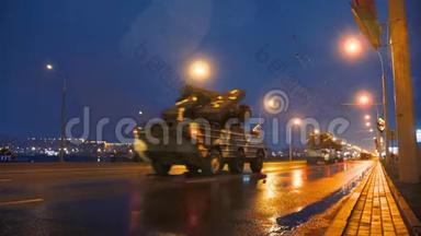 一支军事装备车队在夜间乘坐大灯穿过城市